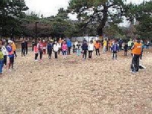 2月2日(日曜)の代々木公園練習会風景(司会者が皆さんの前で説明しています・約60名ほどが写っています)