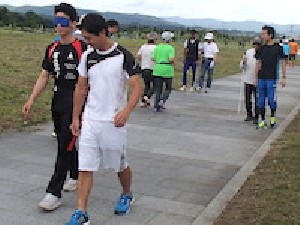 介助方法の体験でアイマスクの男性ペーアとジョギングしている女性ペアーなど数組が写っています。